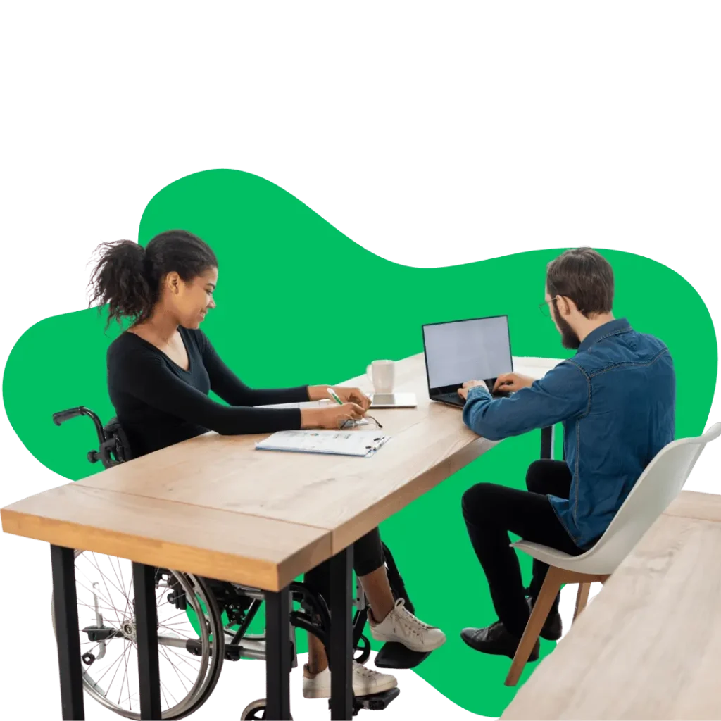 A woman in a wheelchair working at a desk with a male colleague