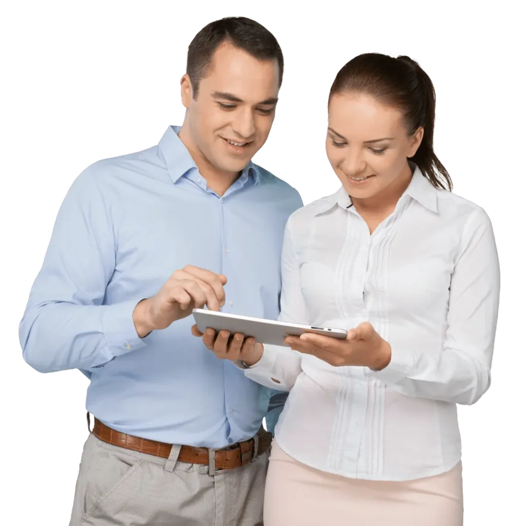 A man and a woman in professional attire smile while reviewing content together on a tablet, indicating teamwork or digital consultation.