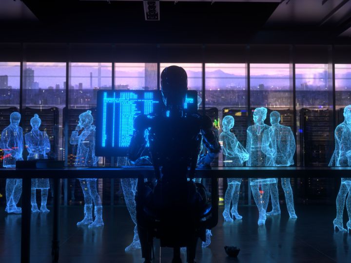 A humanoid robot sits at a desk in front of a glowing digital screen, surrounded by holographic figures of people, inside a futuristic office
